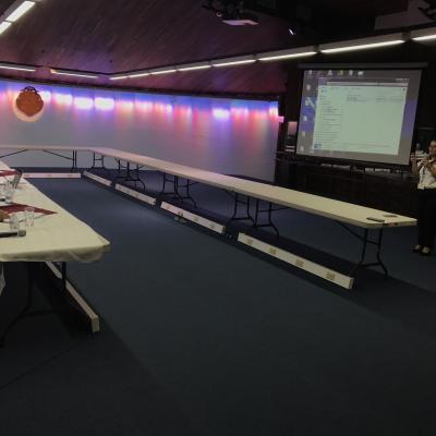 salón con mesas y de fondo se muestra una multimedia