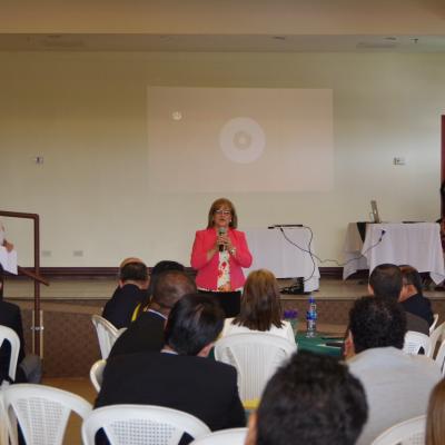 mujer expone de pie al frente y el público la ve 