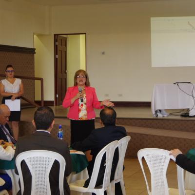 mujer expone de pie al frente y el público la ve 