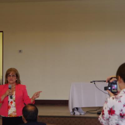 mujer expone de pie al frente y el público la ve 