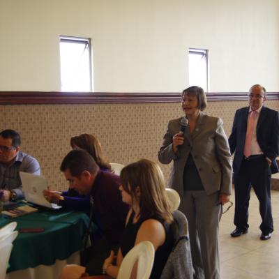 mujer de pie expone con micrófono en mano 