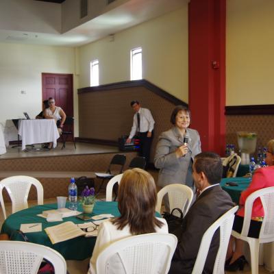 mujer de pie expone con micrófono en mano 