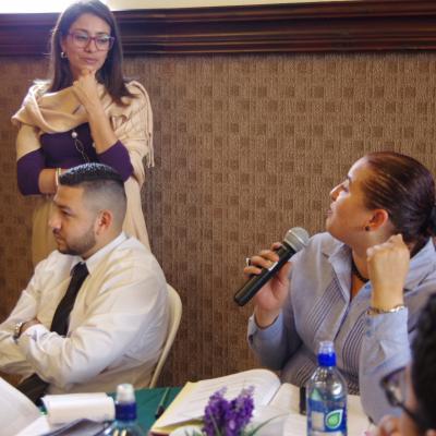 mujer sentada  habla con micrófono en mano 