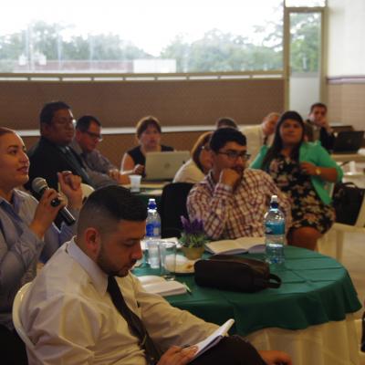 público del evento observando y mujer sentada con micrófono en mano 