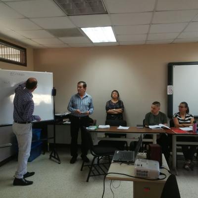 Hombre presentando información a sus compañeros por medio de una pizarra