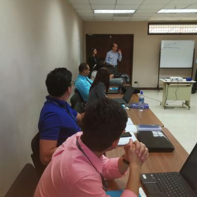 Grupo de personas sentadas poniendo atención a dos presentadores