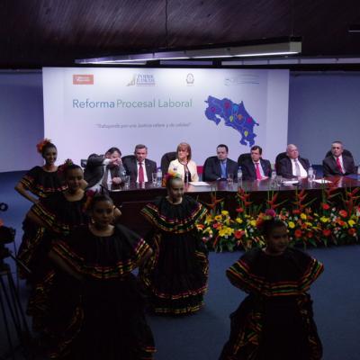 Ejecutivos  sentados  observando a  niños bailando tipico 