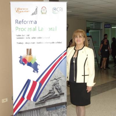 mujer de blanco de pie, al lado banner con mapa de Costa Rica