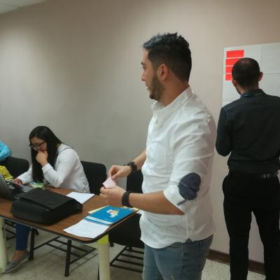 Hombre de pie y mujer sentada en su escritorio