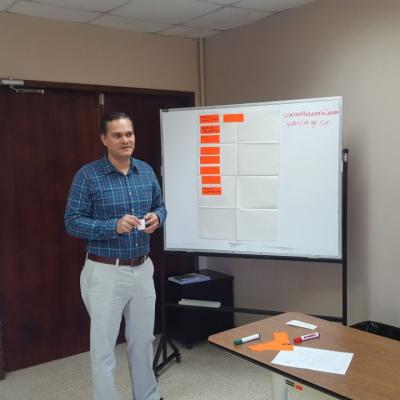 Hombre presentando información junto a pizarra llena de ideas