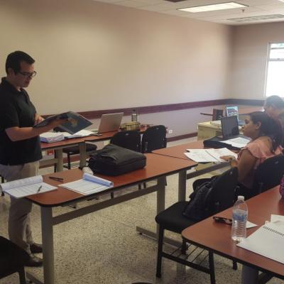 Hombre conversando con mujer sentada en escritorio
