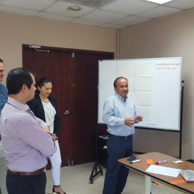 Hombre presentando información a sus compañeros junto al pizarrón