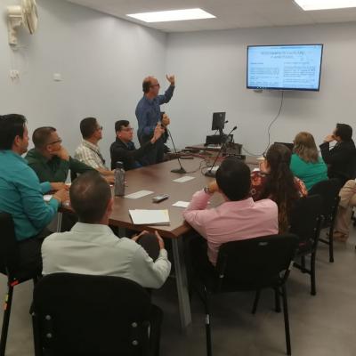 Grupo de personas viendo presentación de compañero