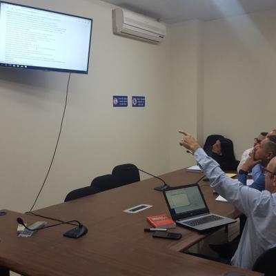Hombre señalando información de la televisión a compañeros