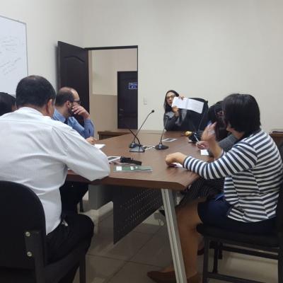 Grupo de personas sentadas escuchando a otra compañera hablar