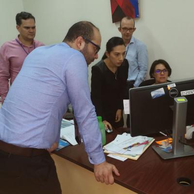 Hombres y mujeres reunidos viendo información en una computadora