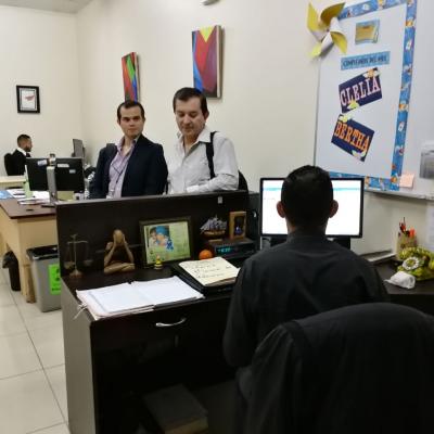 Dos hombres solicitando información a joven usando computadora