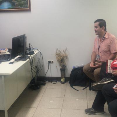 Hombre sentado y hablando con personas en oficina