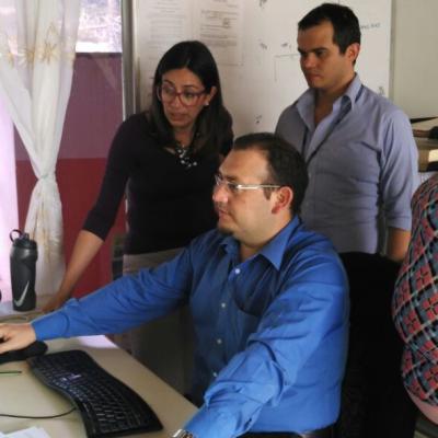 Tres personas de pie y una sentada observando una computadora 