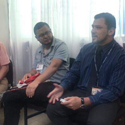 Tres hombres sentados dialogando 