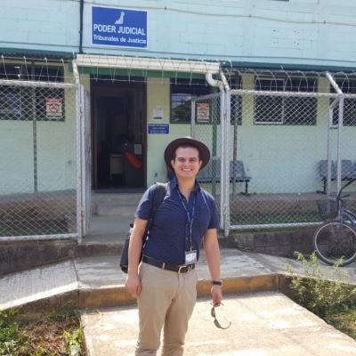 Hombre de pie sonriendo fuera de las oficinas del Poder Judicial
