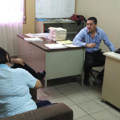 Hombre sentado en su escritorio hablando con compañeros