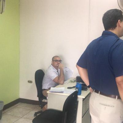 Hombre sentado junto con dos compañeros de pie en su escritorio