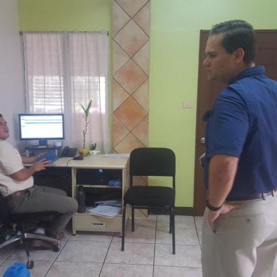 Un hombre sentado en su escritorio junto a su compañero de pie