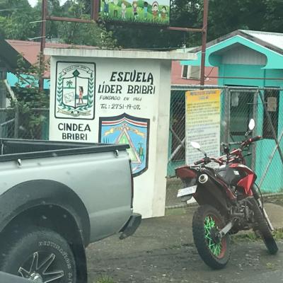 Motocicleta y carro afuera de la escuela Líder Bribrí