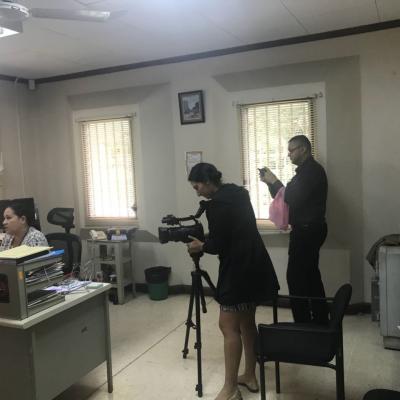 Mujer grabando con cámara de video y hombre grabado con celular a mujer en escritorio