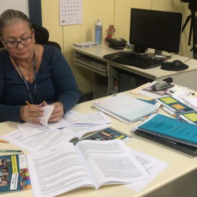 Mujer sentada revisando información y folletos en escritorio 