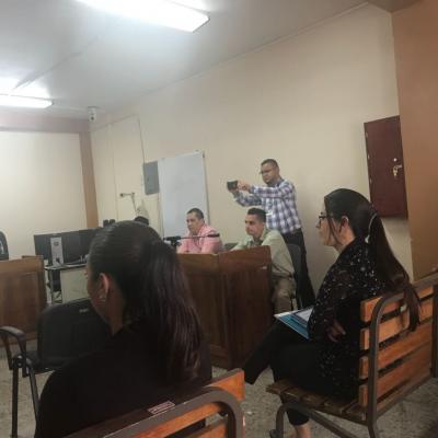 Seis personas sentadas y un hombre de pie tomando una fotografía