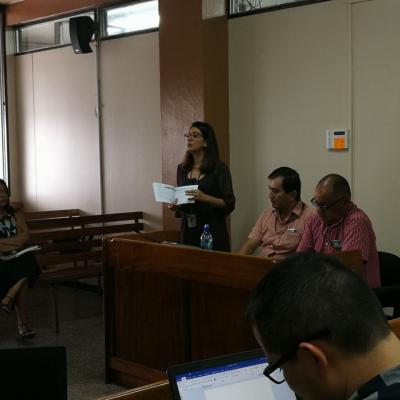 Dos hombres sentados y una mujer de pie debatiendo
