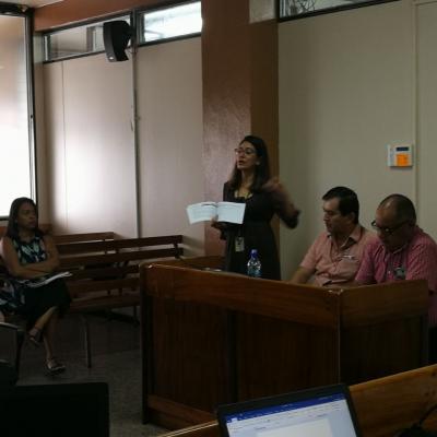 Tres personas sentadas y mujer de pie debatiendo