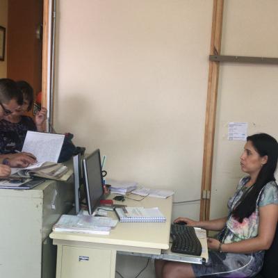 Mujer en su oficina atendiendo a dos personas 