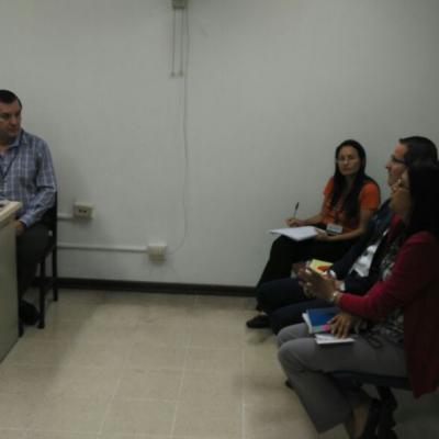 Hombre sentado en su escritorio atendiendo a un grupo de personas