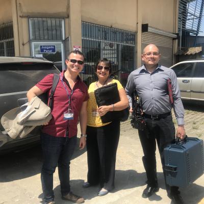 Dos hombres y una mujer de pie sonriendo