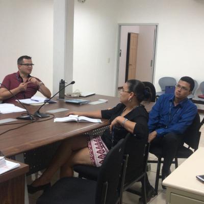 Tres personas sentadas discutiendo en una sala de reuniones