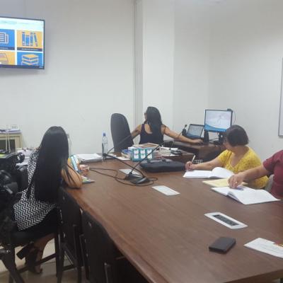 Personas en la sala de reuniones observando un monitor que proyecta un sitio web