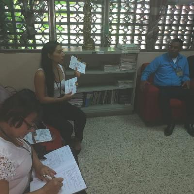 Grupo de personas reunidas y mujer mostrando unos documentos