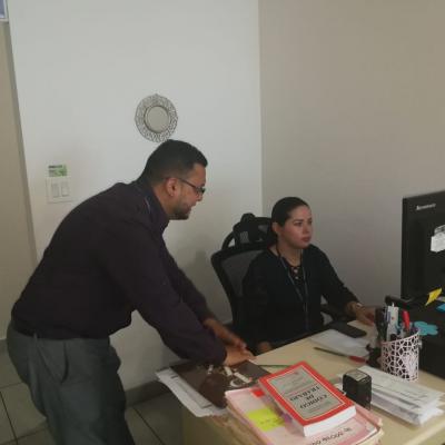 Mujer utilizando una computadora y su compañero de trabajo observando 
