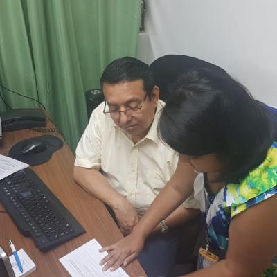 Mujer de pie explicándole a su compañero en el escritorio