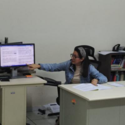 Mujer sentada en su escritorio exponiendo frente a sus compañeros
