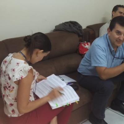 Dos hombres sentados y una mujer leyendo un documento
