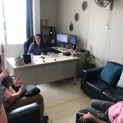 Mujer en su escritorio conversando con dos personas