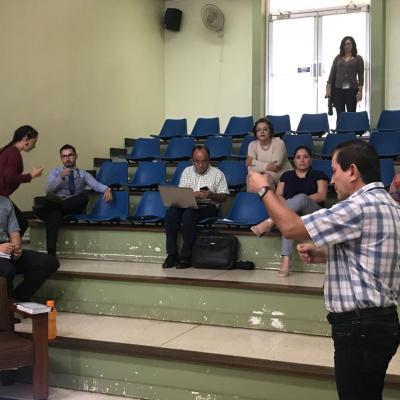 Personas sentadas en unas gradas mientras hombre les habla