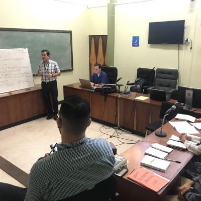 Hombre frente a pizarra explicando a otras personas