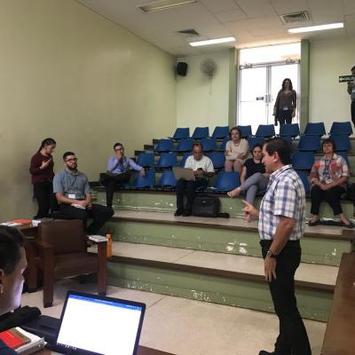 Personas sentadas en unas gradas mientras hombre les habla