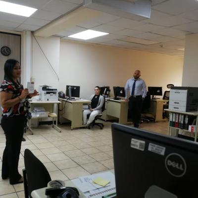 Mujer frente a compañeros de trabajo explicando un documento