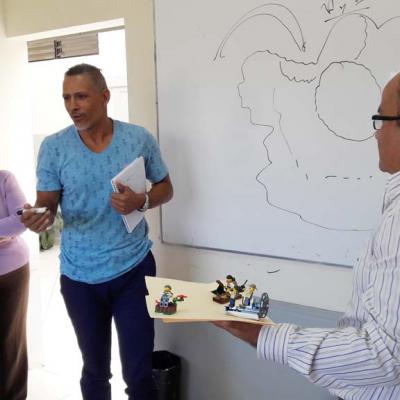 hombre de pie hablando y otro hombre con maqueta en sus manos
